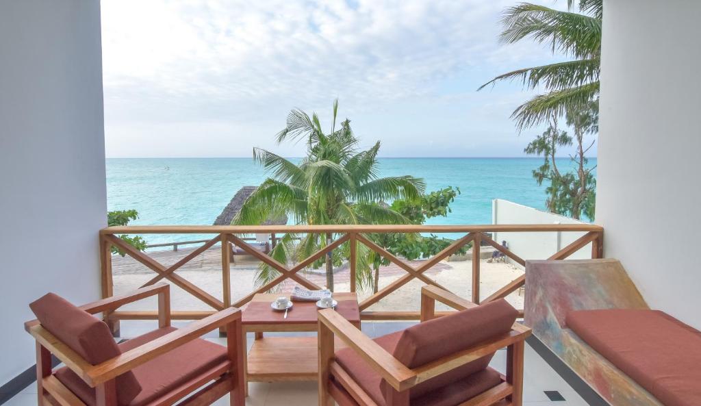 a balcony with chairs and a table and the ocean at Mnarani Beach Cottages in Nungwi
