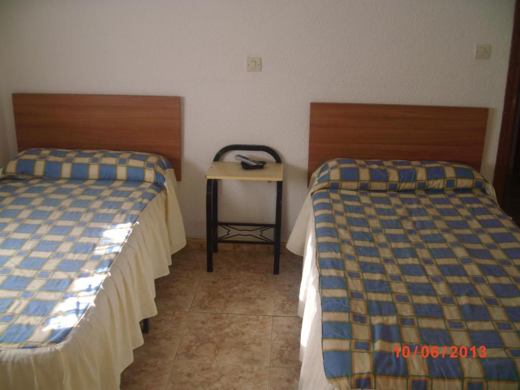 two beds in a hotel room with a table at Pensión Santa Marta in Calatayud