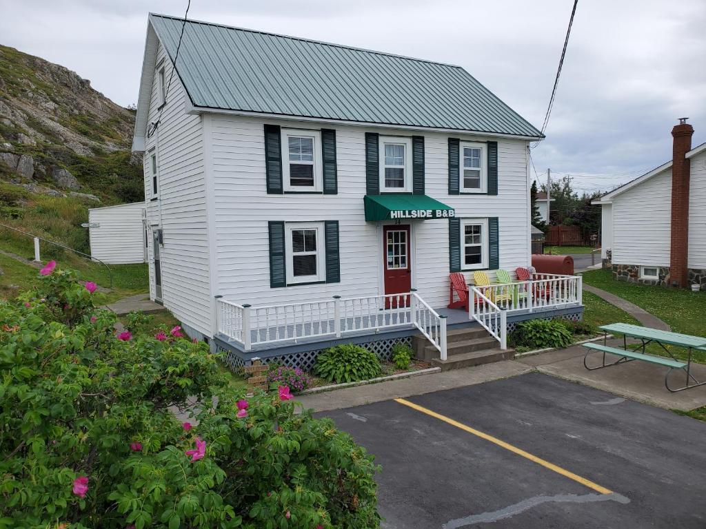 a white house with a red door and a parking lot at Hillside B&B in Twillingate