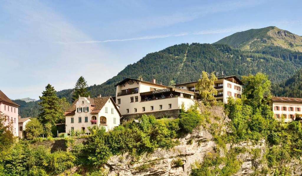 a village on a cliff with mountains in the background at Schlosshotel Dörflinger in Bludenz