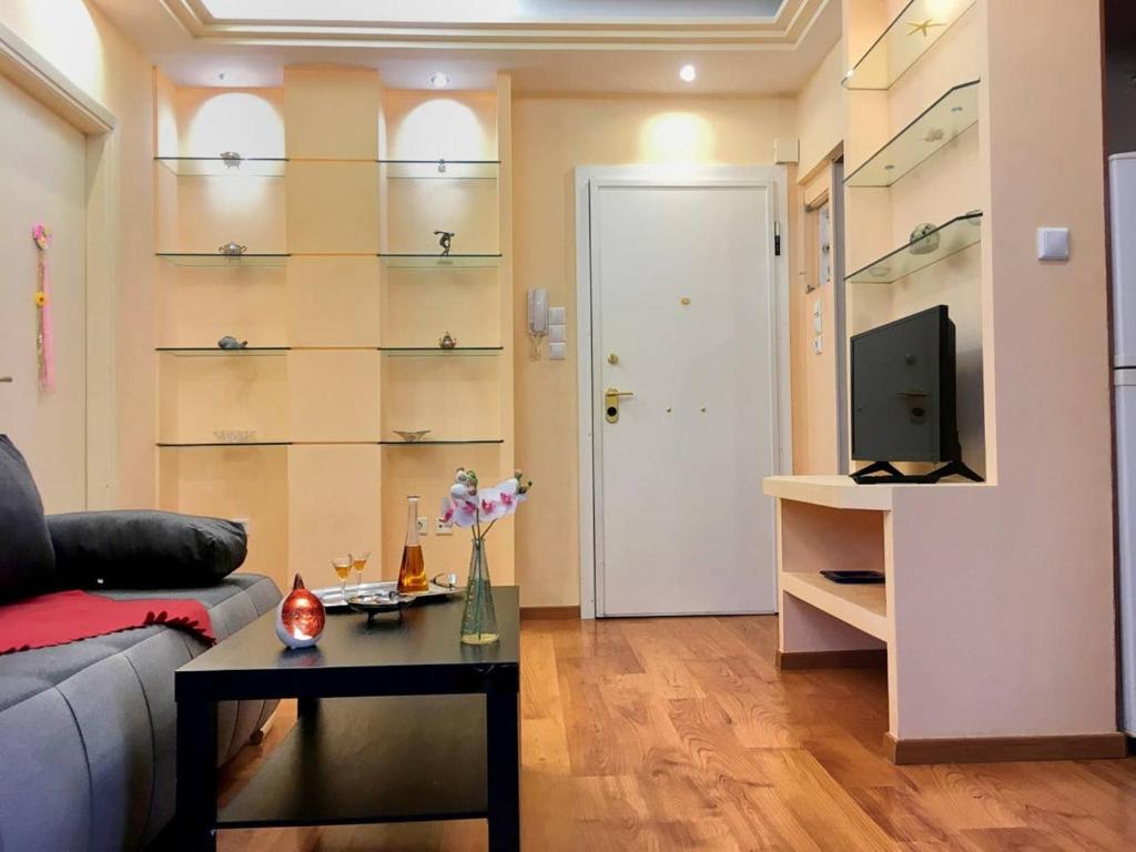 アテネにあるA2 Cute Vouliagmeni Apt in a Unique Spotのソファとテーブルとテレビのあるリビングルーム