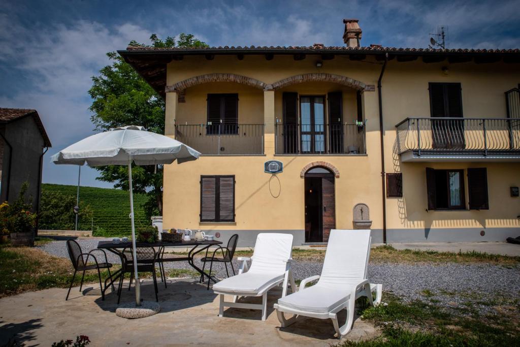 a table and chairs and an umbrella in front of a house at CASA RAMAGIO' in La Morra