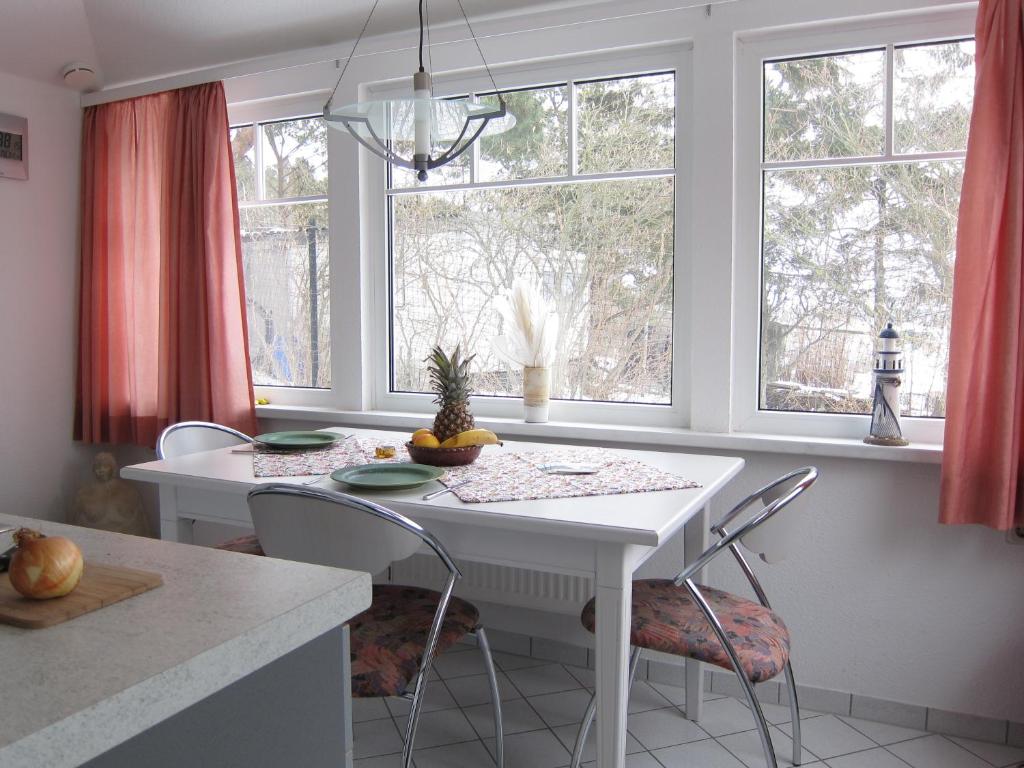 a white table and chairs in a kitchen with windows at Uns Gartenhus mit Blick auf das Meer in Thiessow