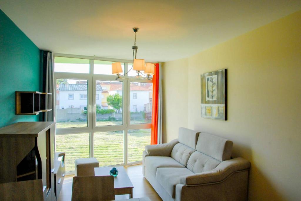 - un salon avec un canapé et une fenêtre dans l'établissement Apartamentos Loncho Finisterre, à Fisterra