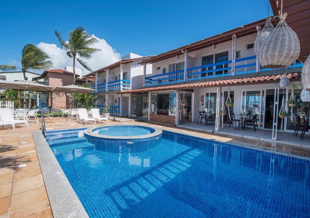 a swimming pool in front of a house at Pousada Olho D'água in Maragogi