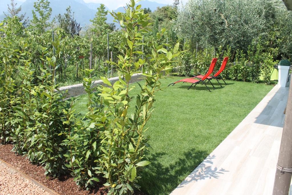 a garden with two red chairs sitting on the grass at Lake & rest in Riva del Garda