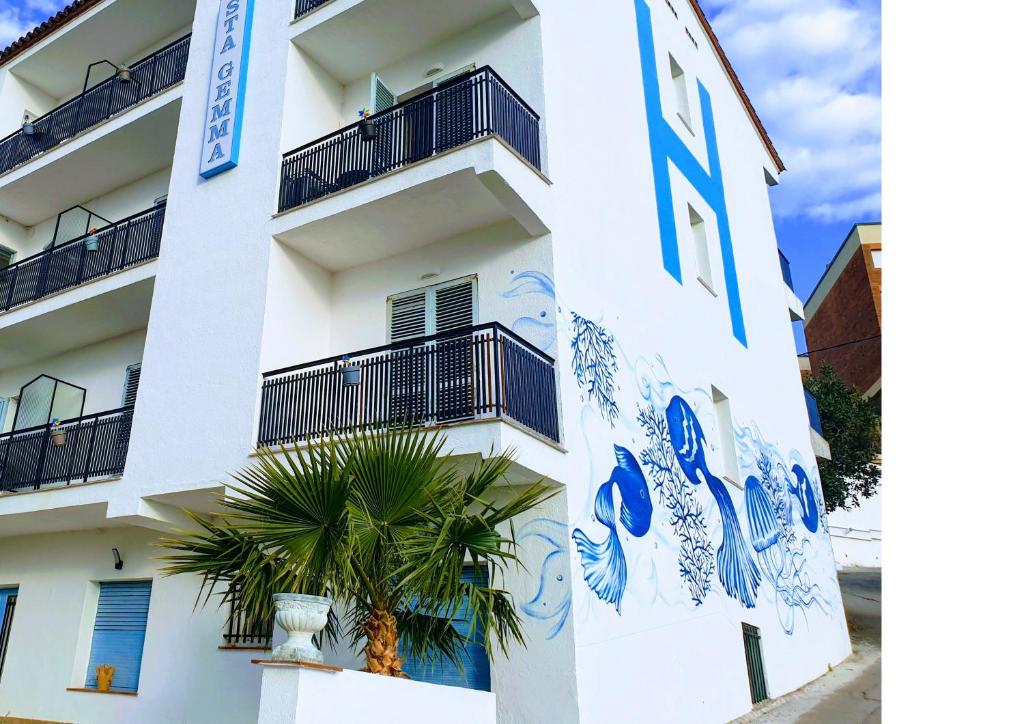 un edificio blanco con una palmera delante en Hostal Santa Gemma, en Sant Vicenç de Montalt