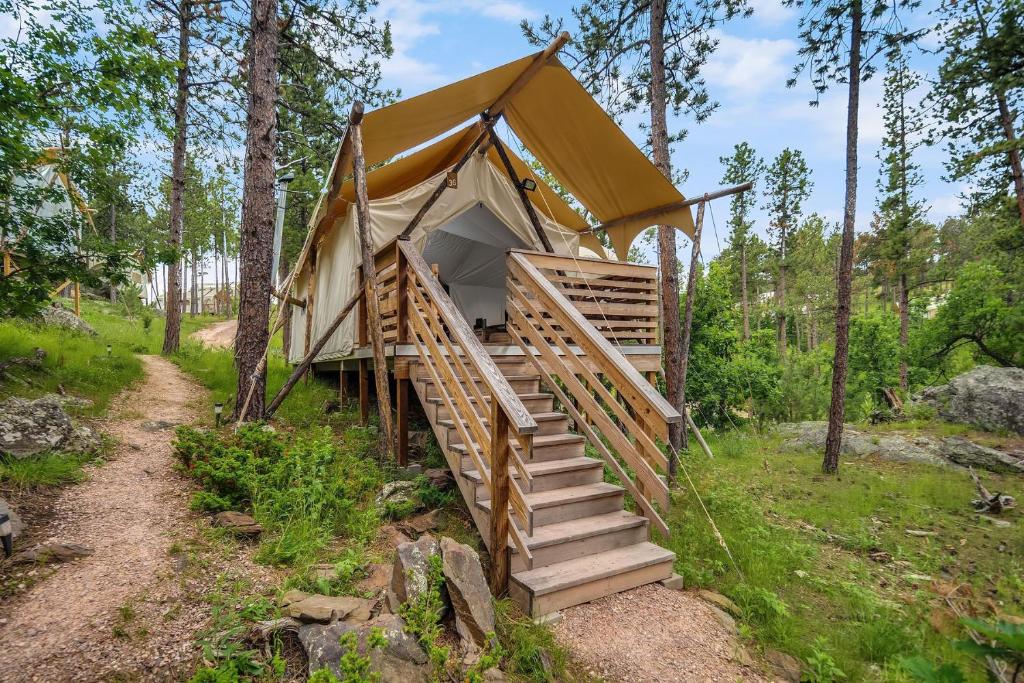 une tente de luxe dans les bois avec des escaliers dans l'établissement Under Canvas Mount Rushmore, à Keystone