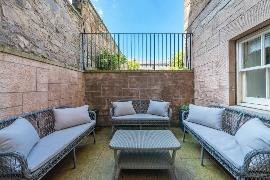 愛丁堡的住宿－JOIVY Luxury 2 bed,2 bath flat with patio, near Calton Hill，砖墙上配有两把椅子和一张桌子的庭院
