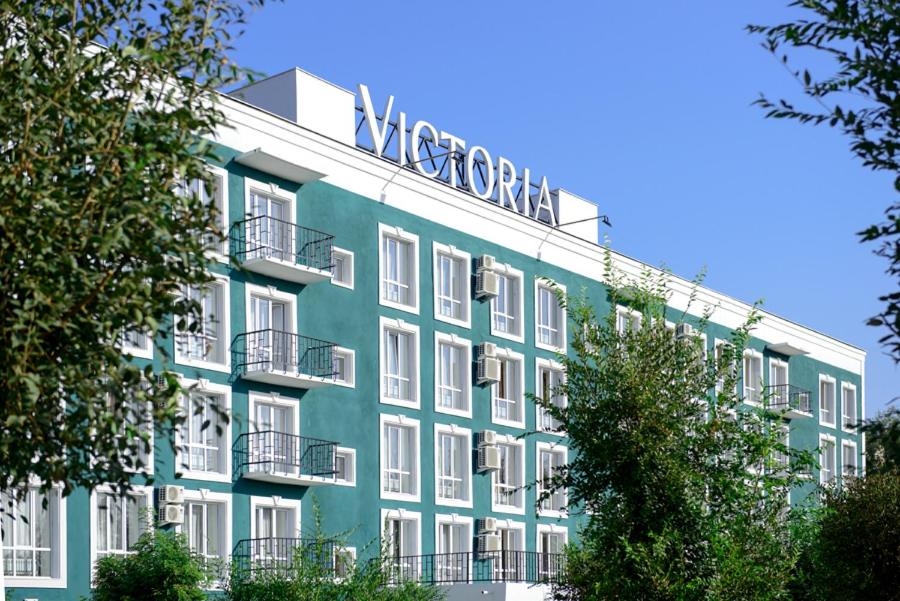 a green building with a sign on top of it at Hotel Victoria in Kapchagay