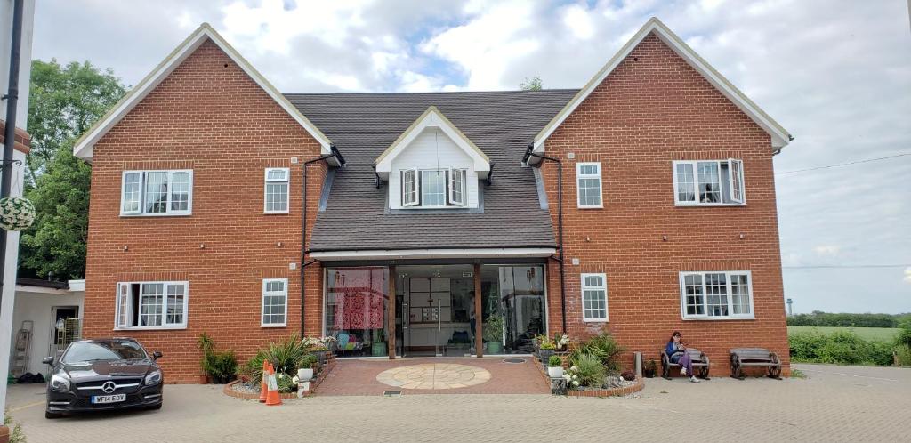a large brick house with a woman sitting in front of it at Stansted Airport Lodge in Takeley