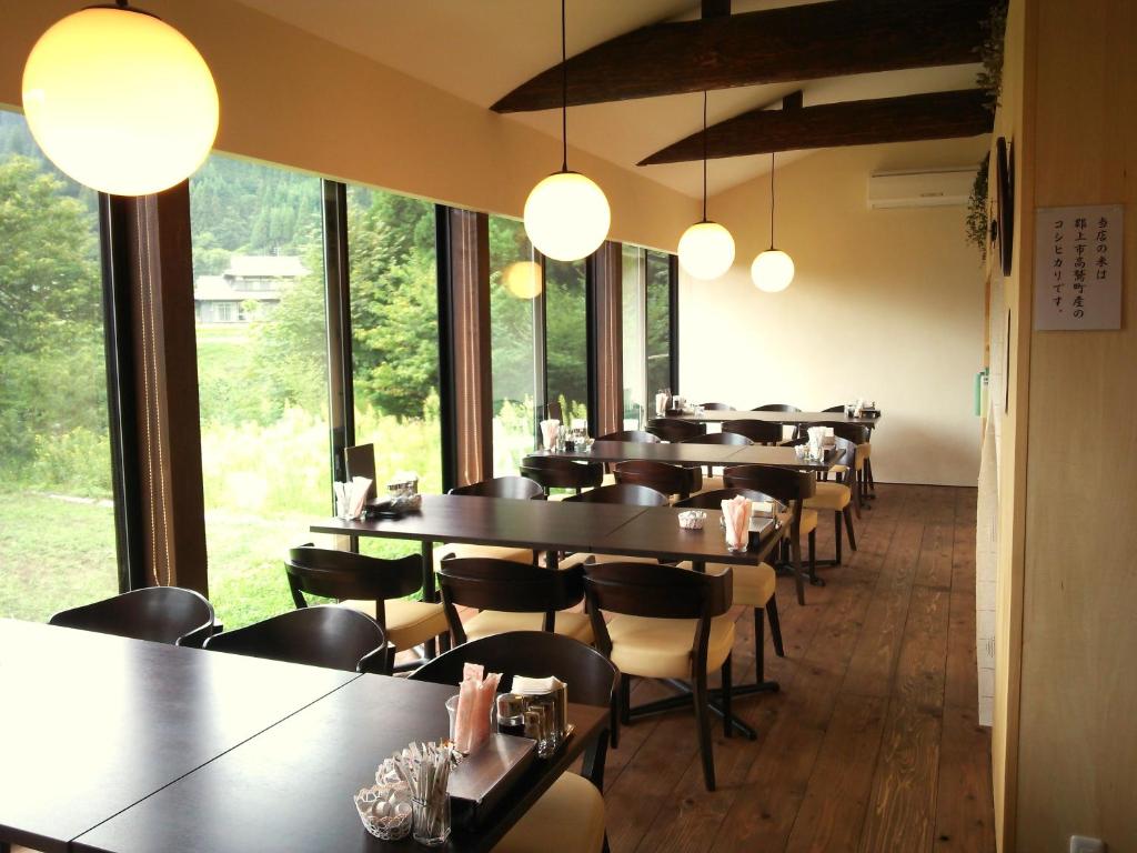 a row of tables and chairs in a room with windows at Kozaemon in Gujo