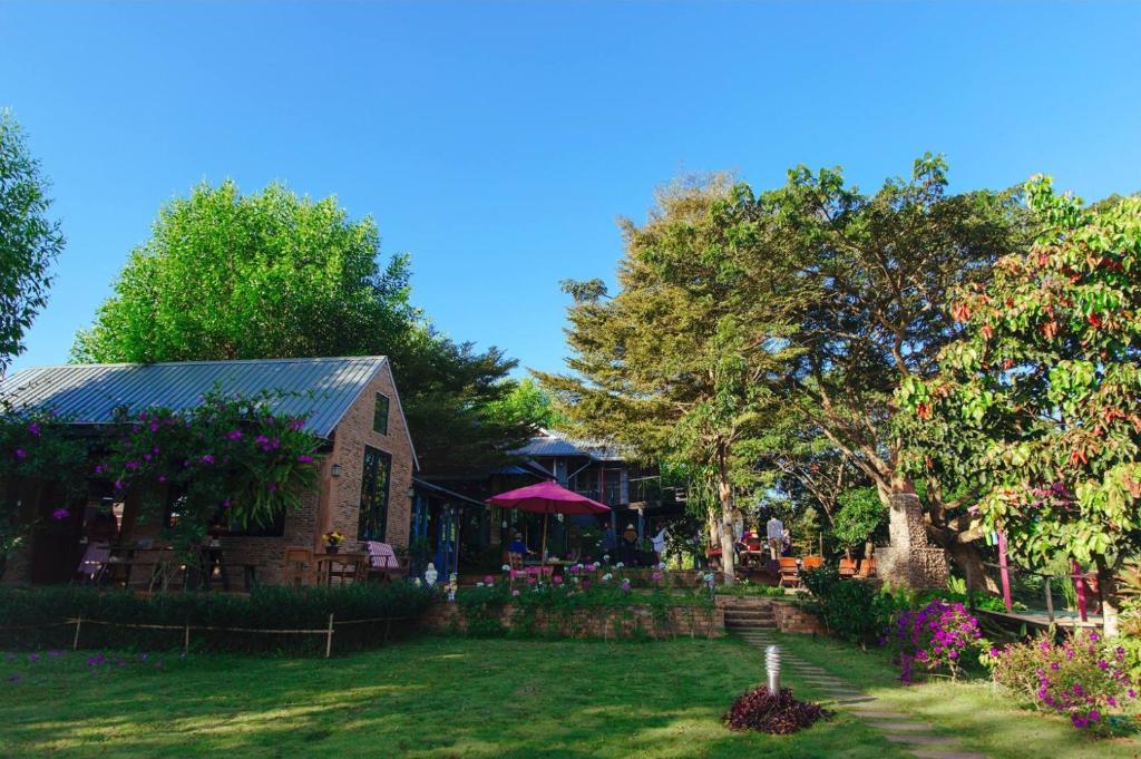 a house with a yard with flowers and trees at Gumbie House in Fang