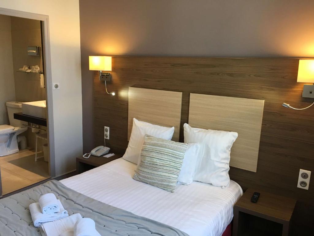 Cette chambre comprend un lit avec des draps et des oreillers blancs. dans l'établissement Best Western Hôtel De France, à Chinon