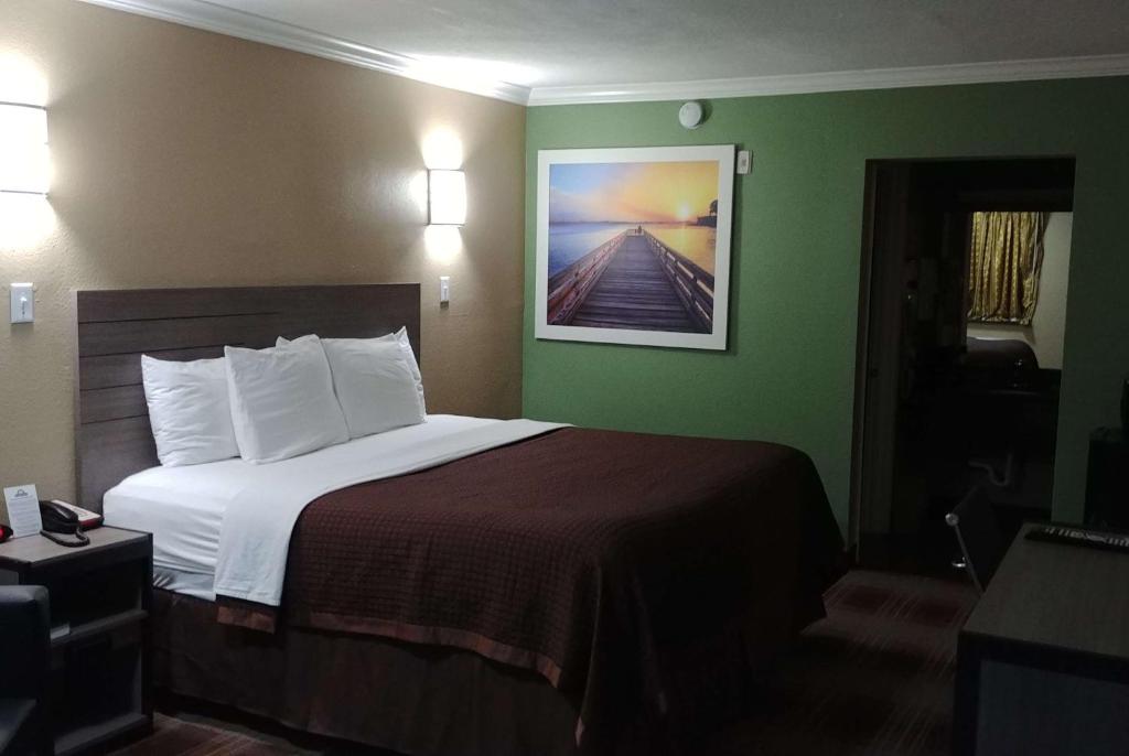 a hotel room with a bed and a painting on the wall at Days Inn by Wyndham Houston East in Houston