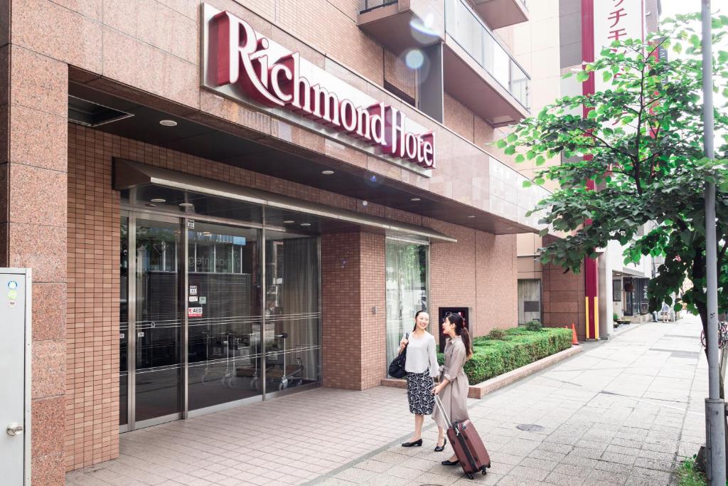 Duas mulheres estão do lado de fora de um edifício. em Richmond Hotel Sapporo Odori em Sapporo