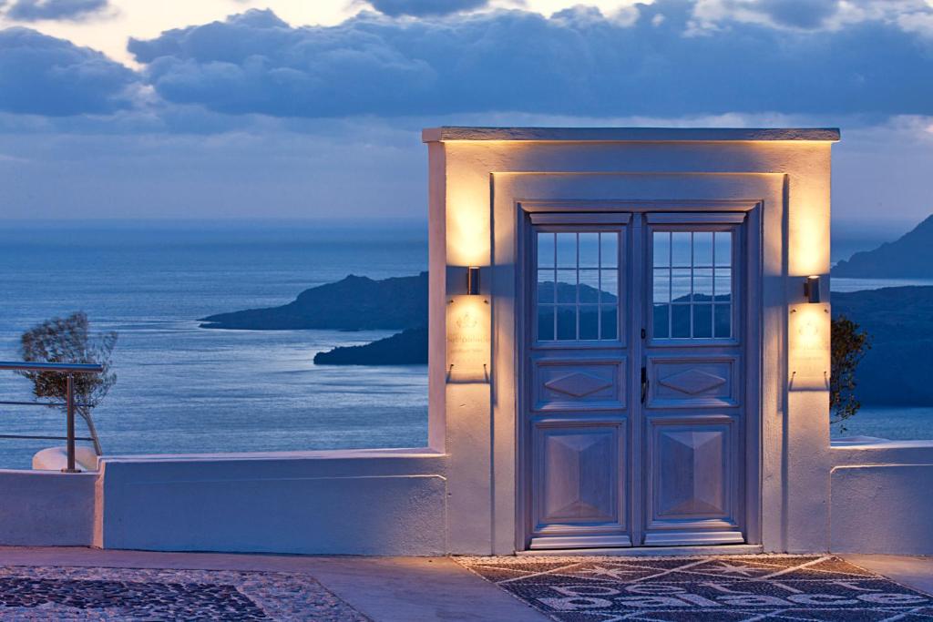 a door with a view of the ocean at Petit Palace Suites in Fira