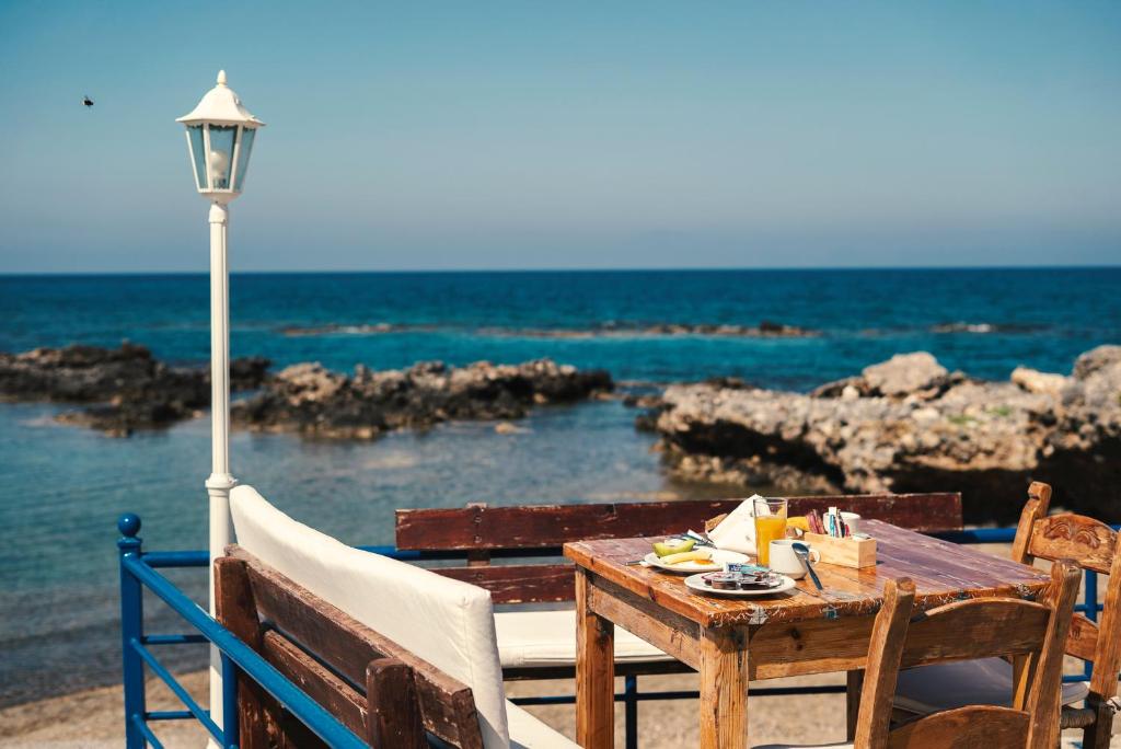 a wooden table and chairs next to the ocean at Coral in Frangokastello