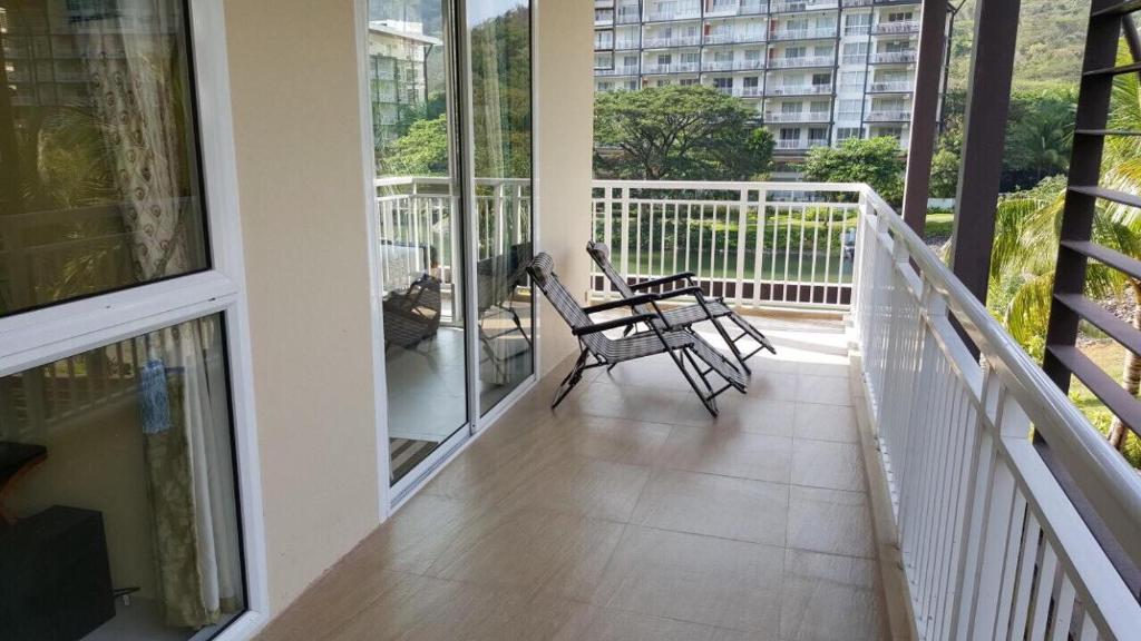 a balcony with two chairs and tables on a building at Creys Condo 2 at Pico de Loro Cove in Nasugbu