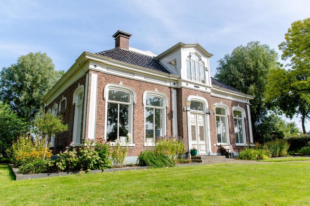 a large brick house with a lawn in front of it at Uitzicht op de haven in Kollum