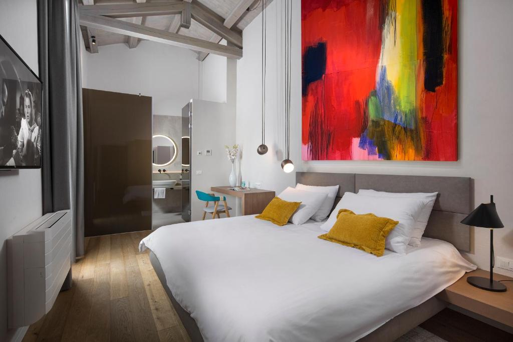 una camera con un letto bianco e un dipinto sul muro di Luxury Town House Corto Bechera a Bale (Valle)