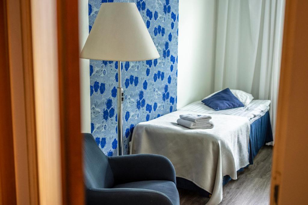 een slaapkamer met een bed, een lamp en een stoel bij B&B Mierontie Oy in Konnevesi