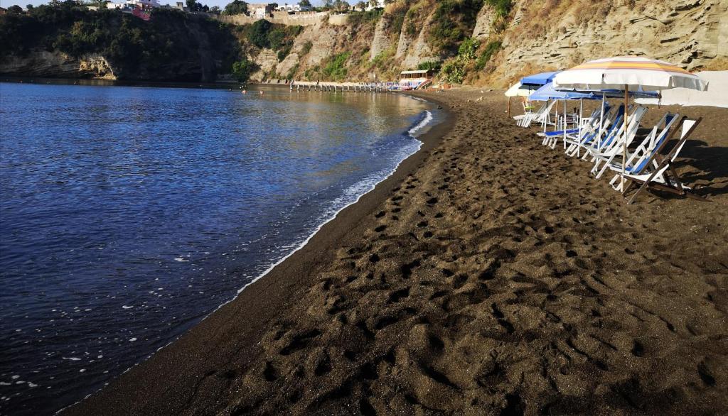 um grupo de cadeiras e guarda-sóis numa praia em Calise guest house B em Procida