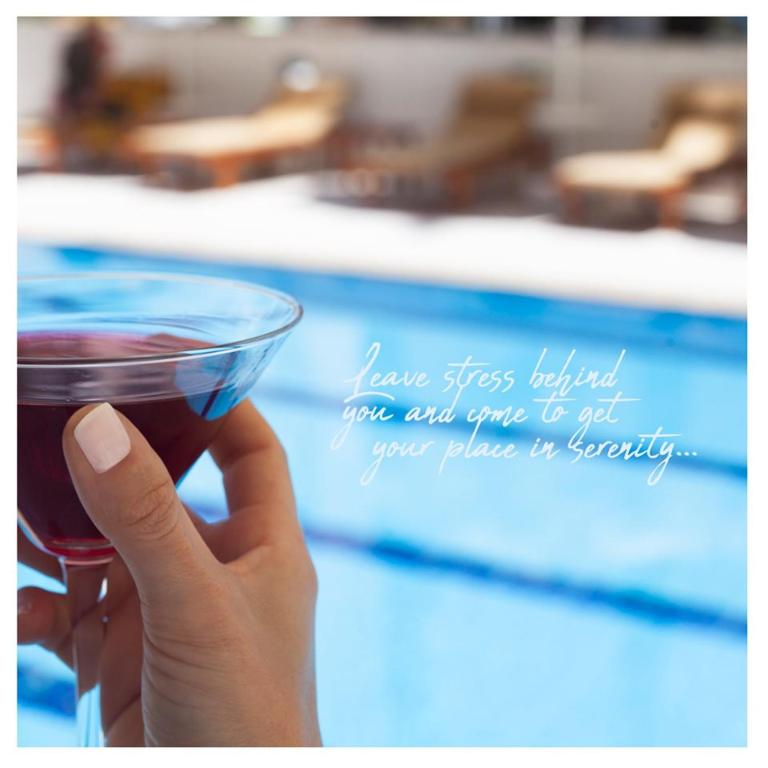 a hand holding a cup of coffee in front of a pool at Lara Park Hotel in Antalya