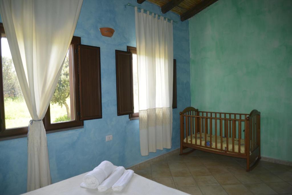 Agriturismo Rubinu في غالنيلي: غرفة نوم زرقاء مع سرير أطفال ونوافذ