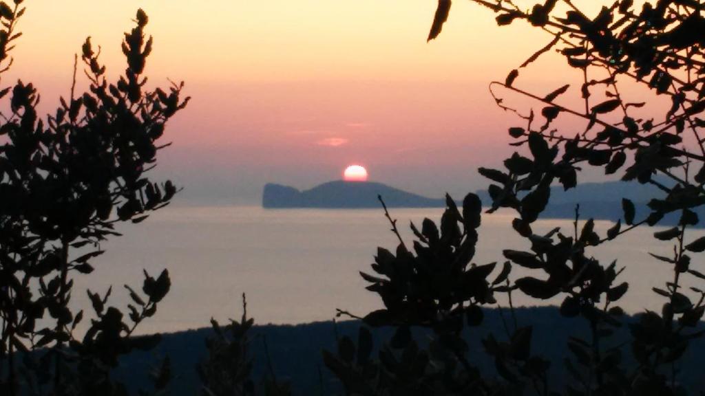 zachód słońca nad oceanem i słońce na niebie w obiekcie Il Giardino Degli Iris w mieście Alghero