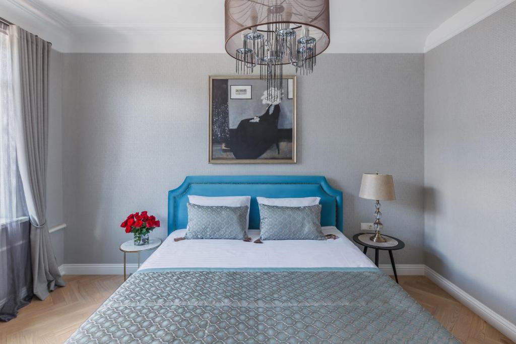 a bedroom with a blue bed and a chandelier at Avenue in Šiauliai