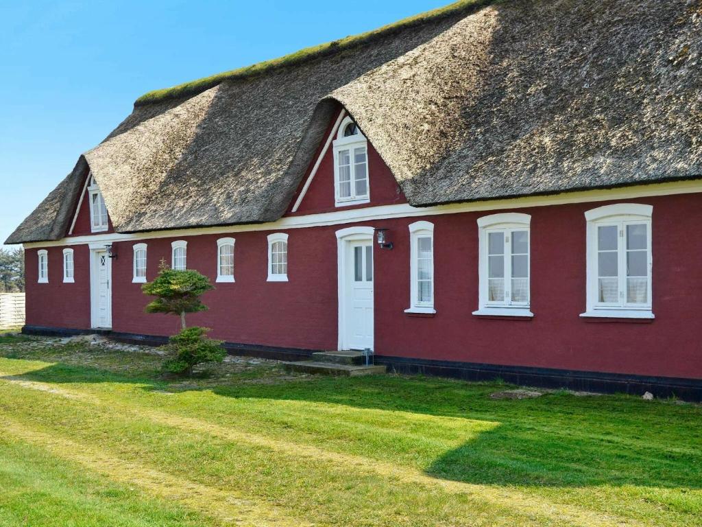 una casa roja con techo de paja en un campo en 4 person holiday home in Fan, en Fanø