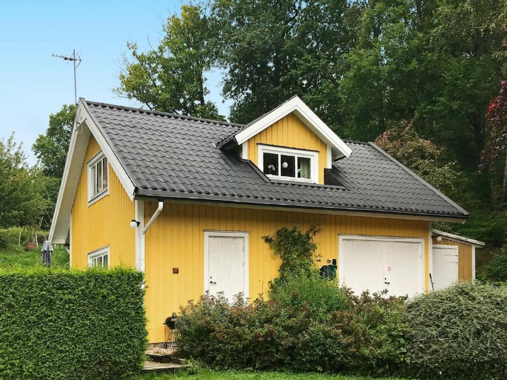 HåverudにあるHoliday Home Håverudの黄色の家 白いガレージのドア2つ