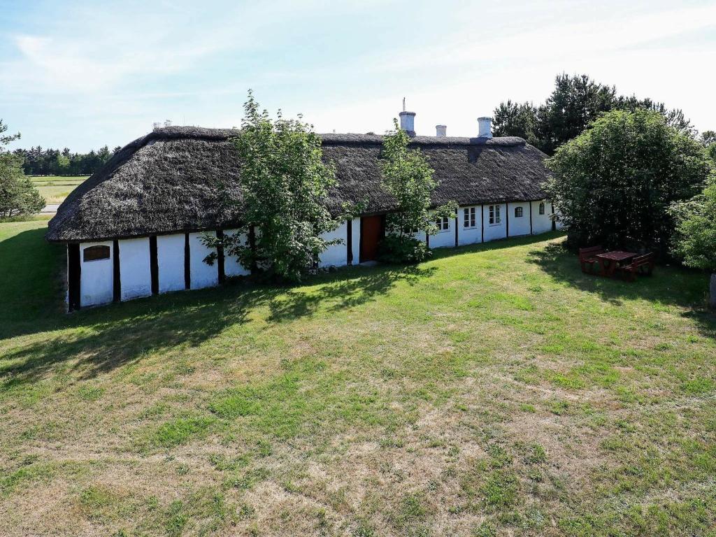 12 person holiday home in L s في Læsø: منزل قديم بسقف من القش وساحة