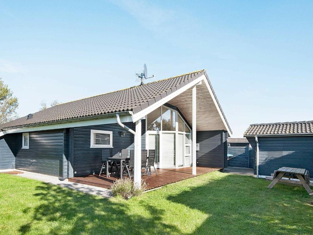 ein blaues Haus mit einer Terrasse mit einem Picknicktisch in der Unterkunft Holiday Home As Hedegård II in Sønderby