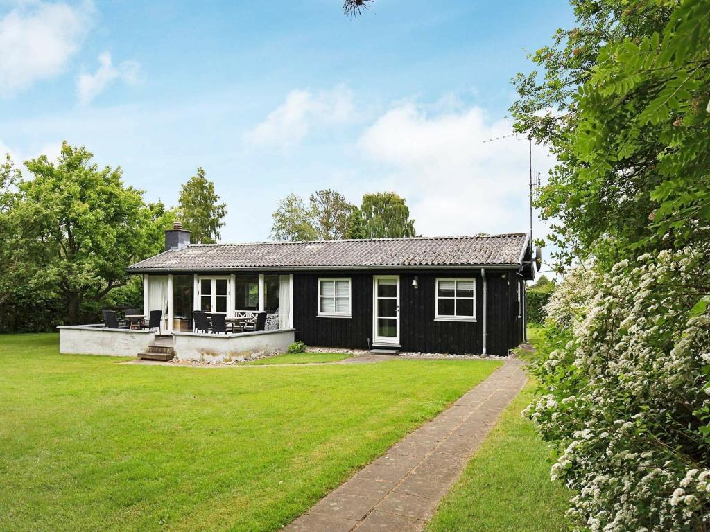6 person holiday home in Dronningm lle في Dronningmølle: منزل أبيض وأسود مع ساحة كبيرة