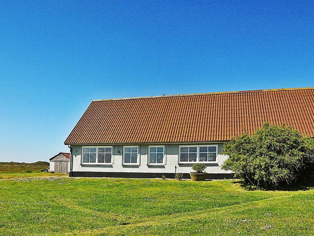 a white house with an orange roof in a field at 6 person holiday home in Hvide Sande in Hvide Sande