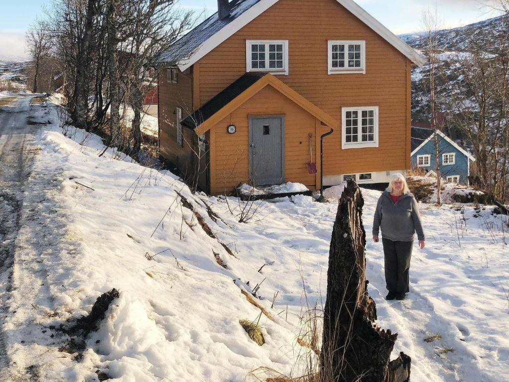 Una donna che cammina nella neve davanti a una casa di Holiday home Skorovatn a Skorovatn