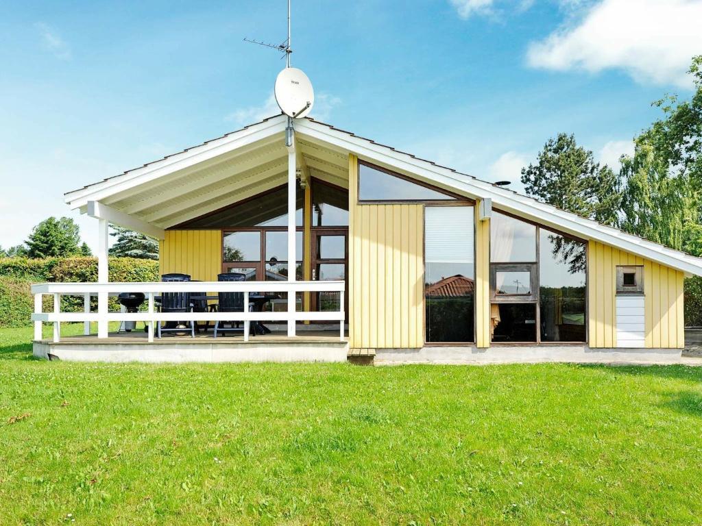 a yellow house with a white fence in a field at Secluded Retreat with Sauna - By Traum Ferienwohnungen in Sønderby
