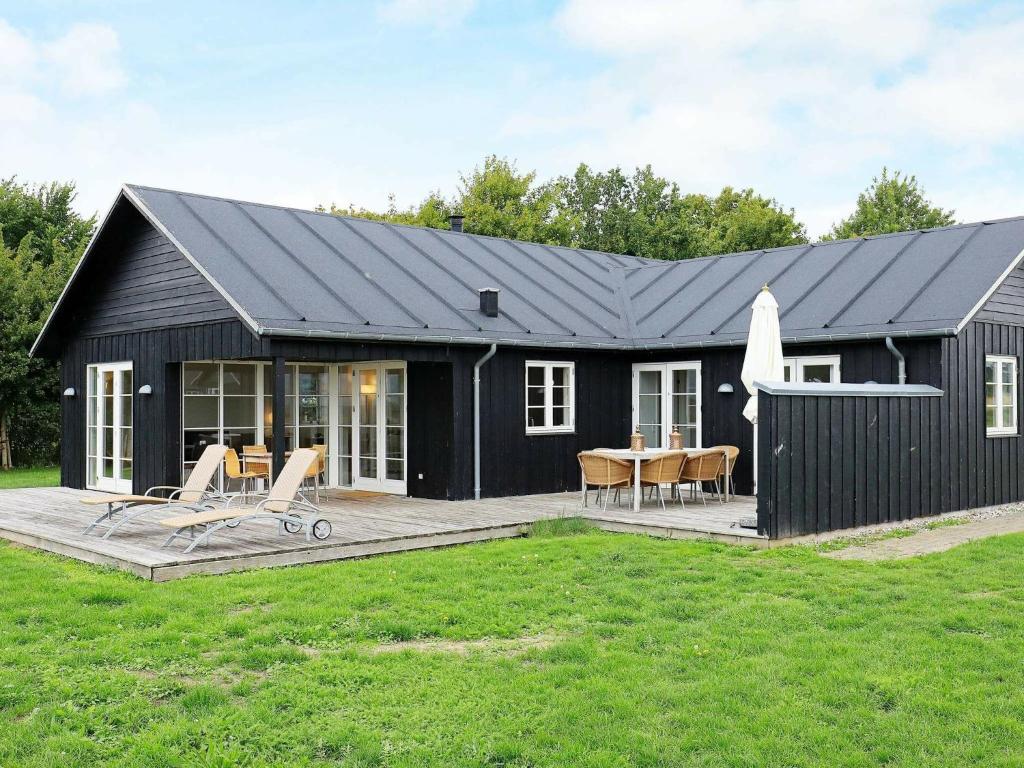 a black house with a deck and a table at 8 person holiday home in Nysted in Nysted