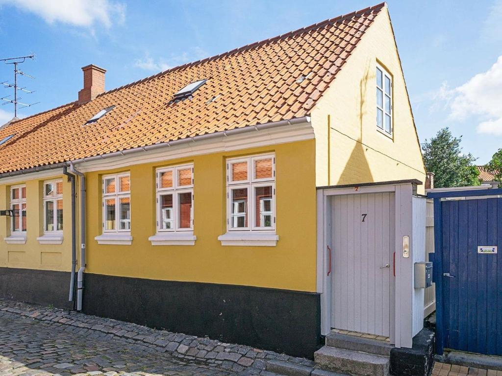 a yellow house with a white door on a street at 5 person holiday home in R nne in Rønne