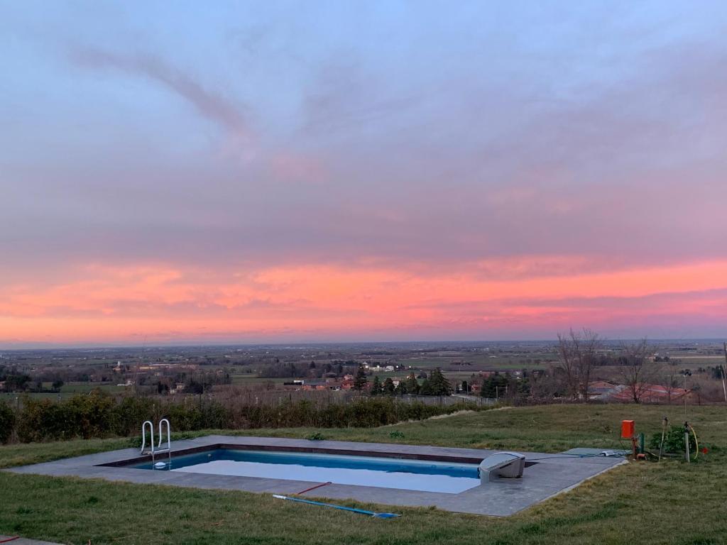 una piscina en la cima de una colina con puesta de sol en Casa Particular, en Castel San Pietro Terme