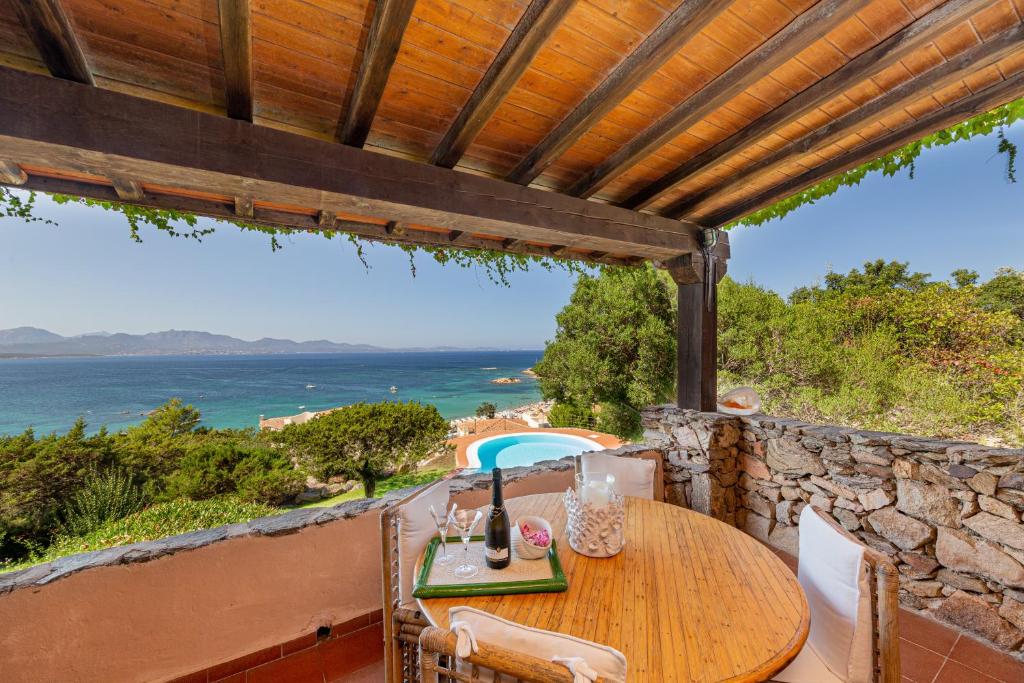 une table en bois sur un balcon avec vue sur l'océan dans l'établissement Villa Romantica, à Olbia