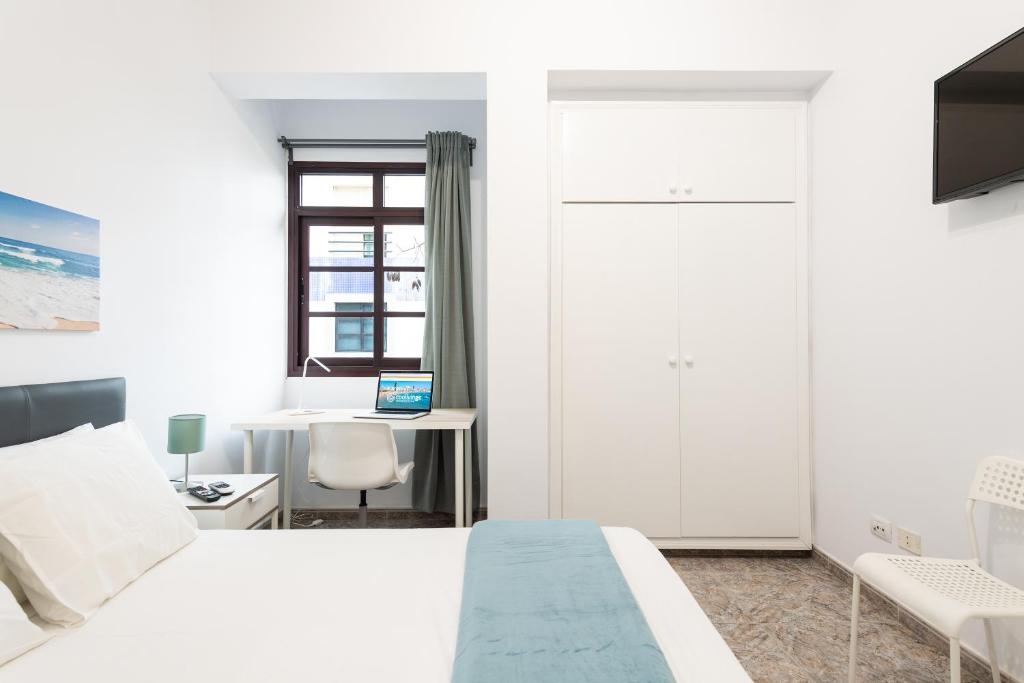 een slaapkamer met een bed en een bureau met een laptop bij CoolivingC in Las Palmas de Gran Canaria