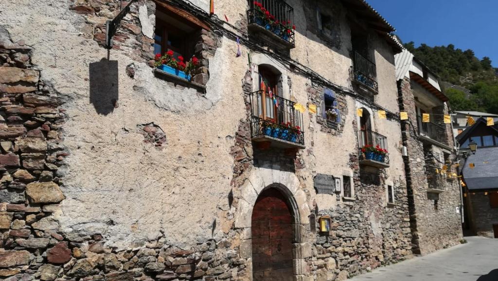 un antiguo edificio de piedra con ventanas y una puerta en Casa Palacin, en Gistaín