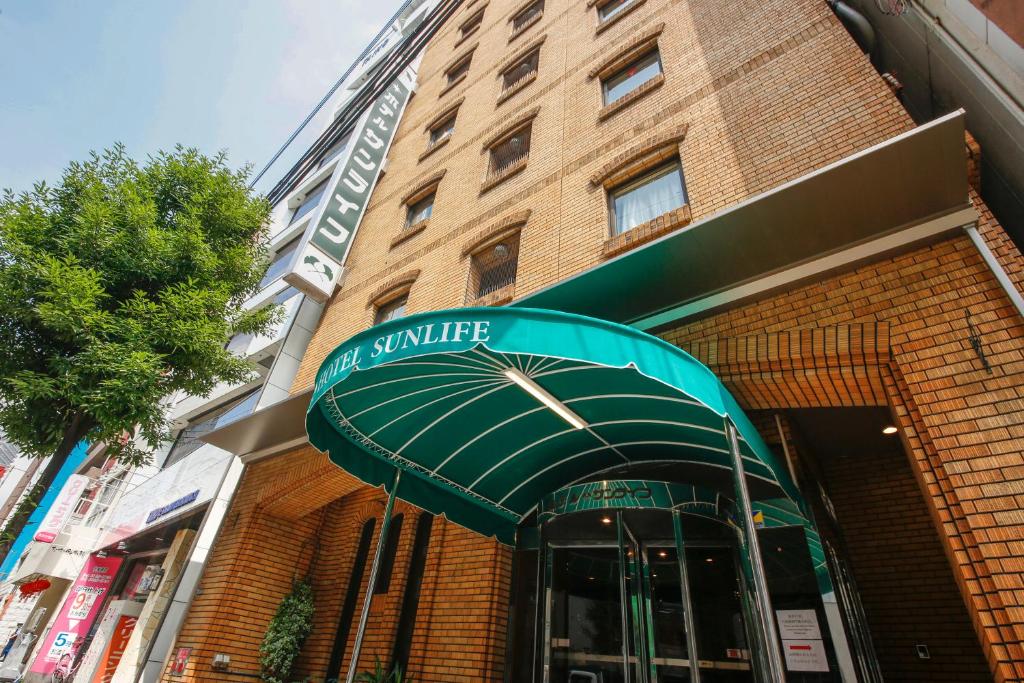 un edificio con un dosel verde delante de él en Hotel Sunlife en Osaka
