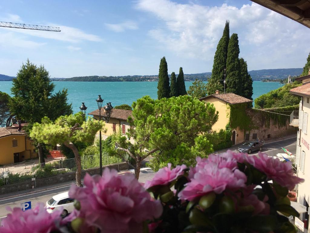 widok na wodę z miasta z różowymi kwiatami w obiekcie Taverna Affittacamere w mieście Gardone Riviera