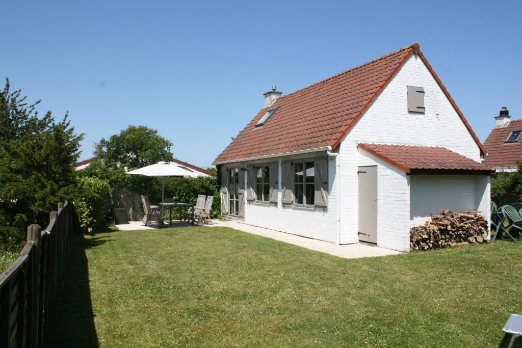 una casa blanca con una valla y un patio en Vakantienestje, en Bredene