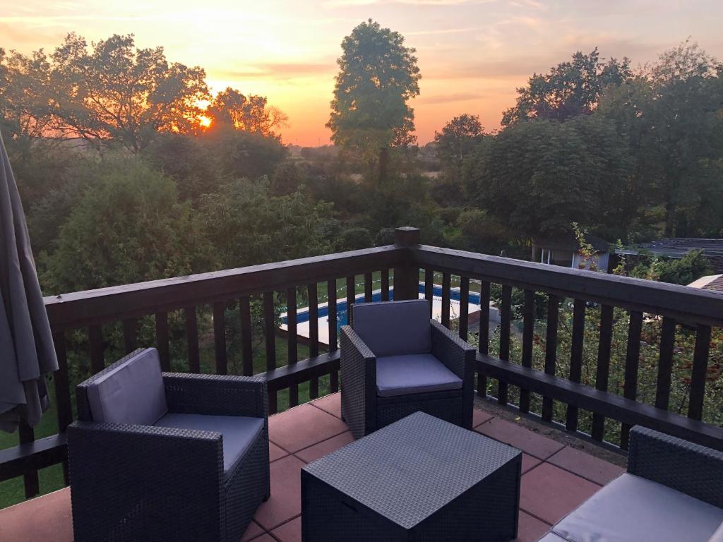 un balcón con 2 sillas, una mesa y una puesta de sol en FeWo Maschblick, en Schwarmstedt