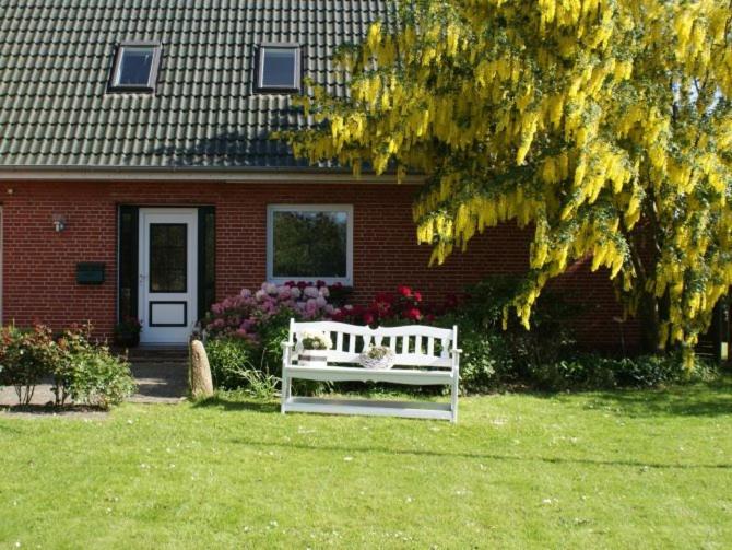 un banc blanc assis devant une maison dans l'établissement Haus Deichblick, à Husum